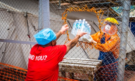 A healthcare worker wearing protective gear hands out water bottles at a treatment centre in the west of Freetown, Sierra Leone.