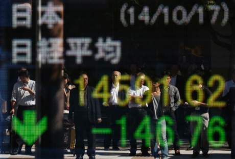 People are reflected in an electronic board displaying the Japan's Nikkei average outside a brokerage in Tokyo October 17, 2014.
