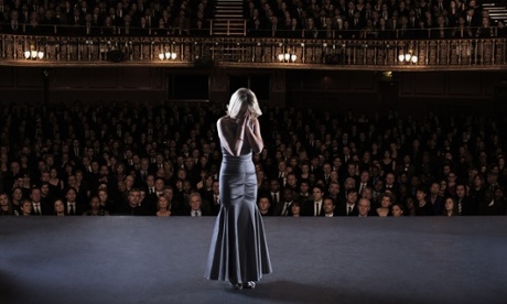 A woman suffering crippling fear of public speaking or stage fright in front of a large audience