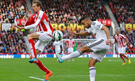 Swansea City's Neil Taylor (R) clears the ball past Stoke City's Peter Crouch