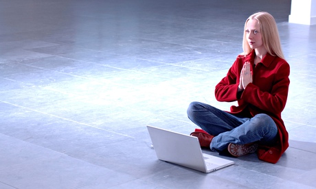 young woman sitting on floor with computer making prayer gesture