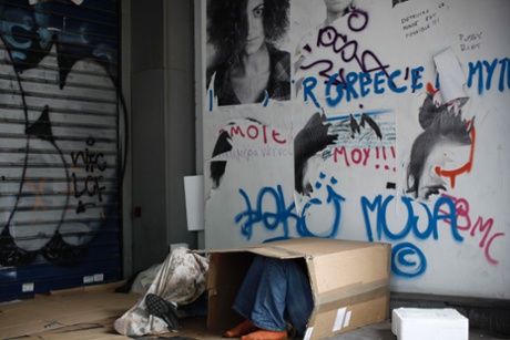 A homeless man uses a cardboard box for shelter in an alleyway in Athens.