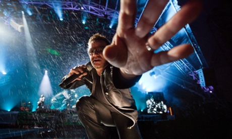 Bono reaches out to take a camera while wearing leather trousers at Glastonbury.