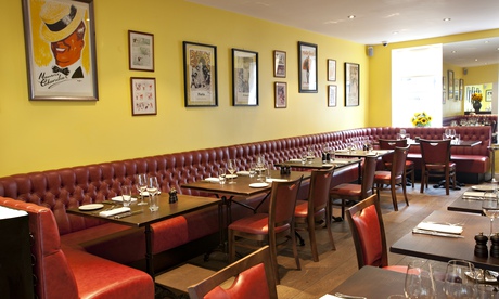 A long banquette along the wall with tables at Brasserie Gustave