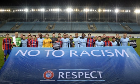 Both sets of players pose behind an anti-racism banner in the empty Khimki Arena