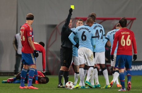 Referee Istvan Vad shows the yellow card to Manchester City's Fernando