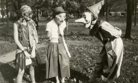 Three girls amuse each other with their masked costumes as they prepare for Halloween festivities in the College Hill neighborhood of Cincinnati, Ohio, 1929. (Photo by Felix Koch/Cincinnati Museum Center/Getty Images)BlackandWhite|116-000|Photograph|Halloween|Costumes|Outdoors|Masks|GirlsSilverPrint