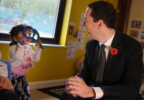 Chancellor of the Exchequer George Osborne smiles as two year old Monica Tamber plays at the Toyota company nursery on October 24, 2014 in Derby, England.