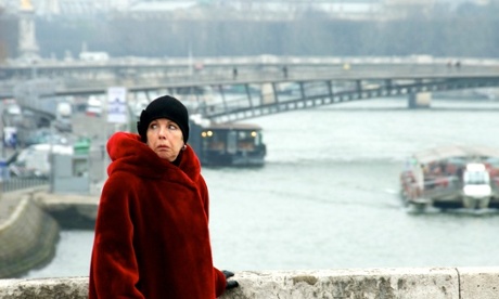 woman in red coat walking across the pont de la concorde in paris