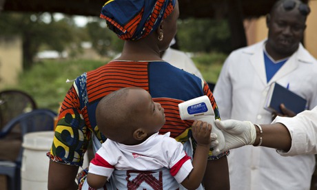 A health worker checks the temperature of a baby entering Mali from Guinea.