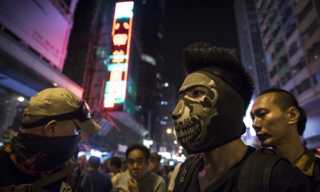 Masked protesters stand at the barriers dividing the police from the crowds in Mongkok on Saturday.