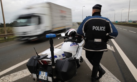A police officer guards the motorway leading to the ferry port in Calais. Hundreds of French police were mobilised last week to restore calm after clashes between migrants, many of whom are trying to get on to trucks heading for Britain.