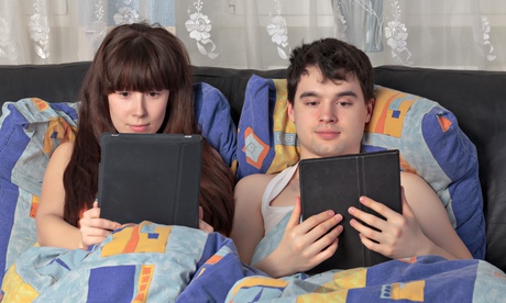 Couple using tablet computers in bed