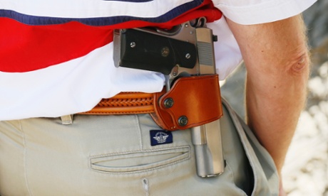 A man carries a .45 Colt pistol as he listens at a rally sponsored by Rocky Mountain Gun Owners, marking the one-year anniversary of the Aurora theatre shootings.