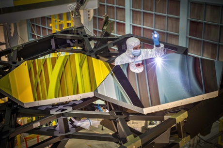 JWST Optical Engineer Larkin Carey from Ball Aerospace examines two test mirror segments recently placed on a black composite structure. This black composite structure is called the James Webb Space Telescope's “Pathfinder” and acts as a spine supporting the telescope's primary mirror segments.
