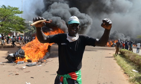 A man stands in front of a burning motorbike in Ouagadougou