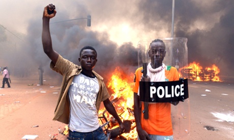 Two young men stand in front of a bonfire outside the parliament building in Ougadougou, Burkina Faso. 