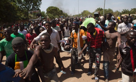 Anti-government protesters carry the injured in a crowed in Ouagadougou, October 30, 2014. 