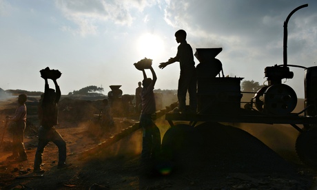 Children carry coal in baskets to a crushing machine at a roadside depot in the Indian state of Megh