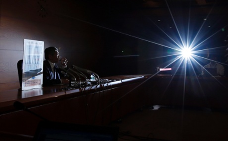 Bank of Japan (BOJ) Governor Haruhiko Kuroda has a drink of water as he sits next to a placard showing BOJ policy decisions during a news conference at the BOJ headquarters in Tokyo October 31, 2014.