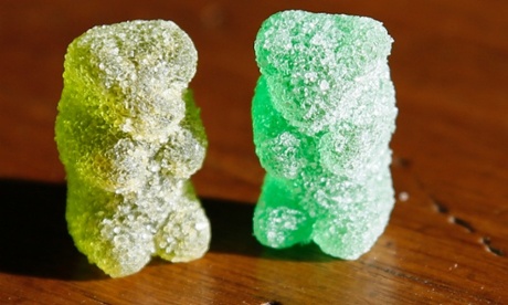 A marijuana-infused sour gummy bear candy is shown next to a regular one in Golden, Colorado.