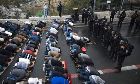 A line of Israeli border police stand guard in front of  Palestinians praying during Friday prayers at the east Jerusalem neighbourhood of Wadi Al Joz, 31 October 2014.