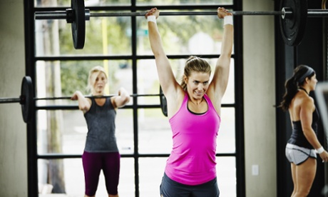 Women doing snatch with barbell in crossfit gym.