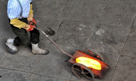 a worker carrying a pig - molten hot piece of iron