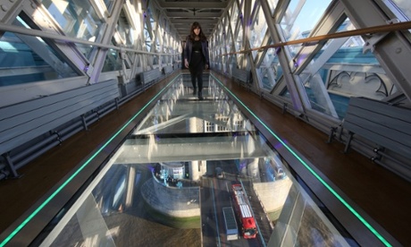 A visitor crosses Tower Bridge's new glass walkway over the River Thames  in London.