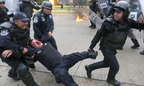 A wounded riot police officer is rescued from violent demonstrators during clashes near Acapulco's airport.
