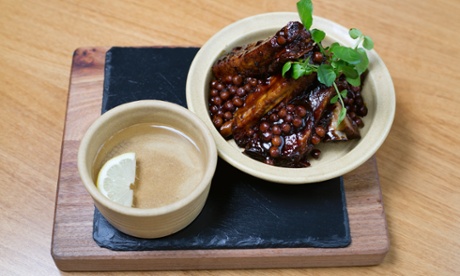 Treacle-baked ribs in a high-sided dish on a wooden platter