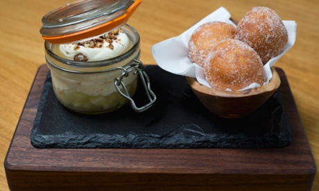 Apple trifle in a jar with on a wooden board with doughnuts in a basket