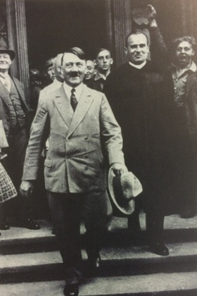 Hans Frank, to Hitler's right and wearing a black cloak, acted as Hitler's lawyer at more than 100 trials prior to 1933.