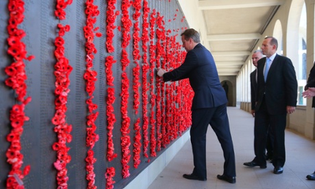 British Prime Minister David Cameron places a poppy in the roll of honour wall as Australian Prime Minister Tony Abbott watches.