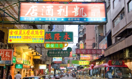 Neon advertising signs hang over a Hong Kong street.