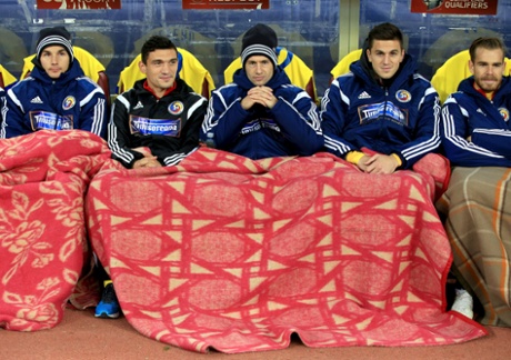 The Romania substitutes keep warm on the bench.