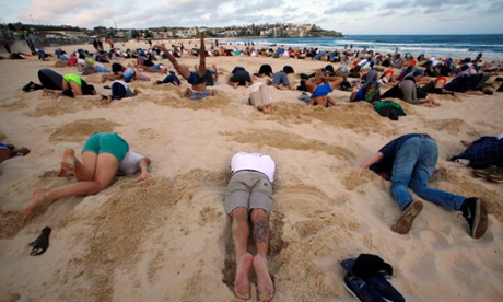 A group of around 400 demonstrators participate in a protest by burying their heads in the sand at Sydney's Bondi Beach.