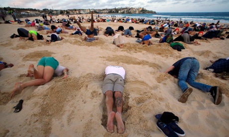About 400 people bury their heads in the sand at Sydney's Bondi Beach ahead of the G20 summit in Brisbane. The group were protesting Australia's reluctance to place climate change firmly on the meeting's agenda.