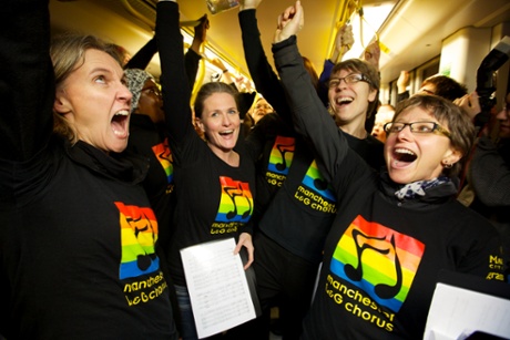 Members of the Manchester Lesbian and Gay Chorus singing on Metrolink trams in Manchester city centre
