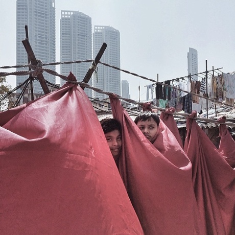 Children peek from behind curtains at Dhobi Ghat.