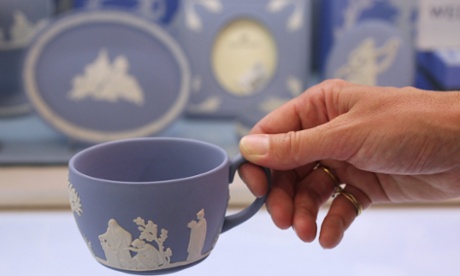 A woman holds a Wedgwood teacup featuring the white and blue ceramic synonymous with the brand.