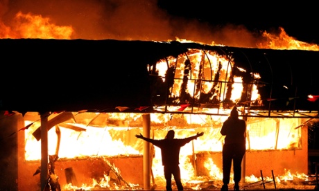 Protesters take their pictures in front of the burning Juanita's Fashion R Boutique on West Florissant Avenue in St. Louis, Mo. early Tuesday, Nov. 25, 2014.