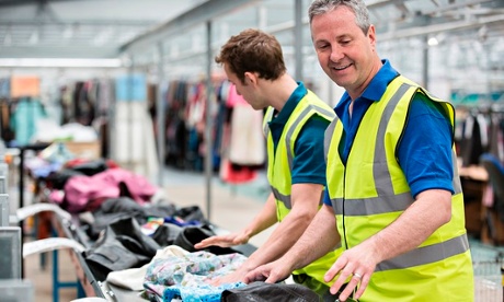 Two men sorting clothes on conveyor belt in warehouse