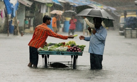 A man buys vegetables on a flooded Mumbai street