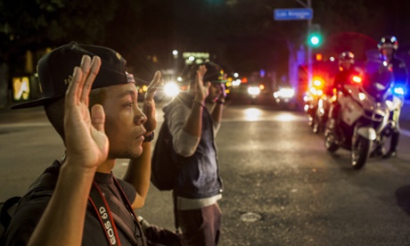 Protesters kneel down with their hands up in front of Los Angeles police officers.