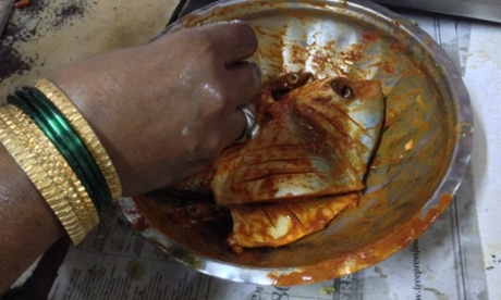 Savita prepares a pomfret for frying with chili and haldi, in Chimbai Village