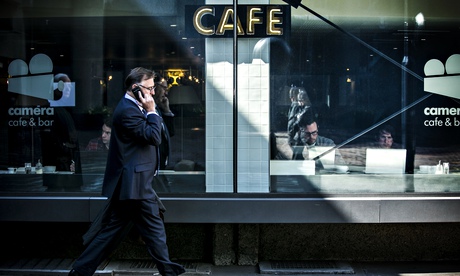 Man on mobile phone walks past cafe