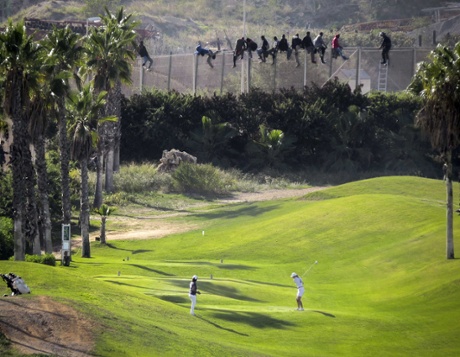 African migrants sit on a border fence during an attempt to cross into Spanish territories between Morocco and Spain's north African enclave of Melilla.