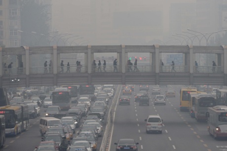 This picture taken on October 8, 2014 shows pedestrians walking through an overpass as commuters drive on a road below in Beijing amid heavy smog.
