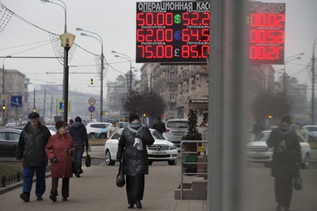 People walk past a display with currency exchange rates in central Moscow, Russia, Monday, Dec. 1, 2014.